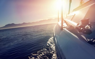 Sailing yacht boat on on ocean water at sunrise with flare and outdoor lifestyle